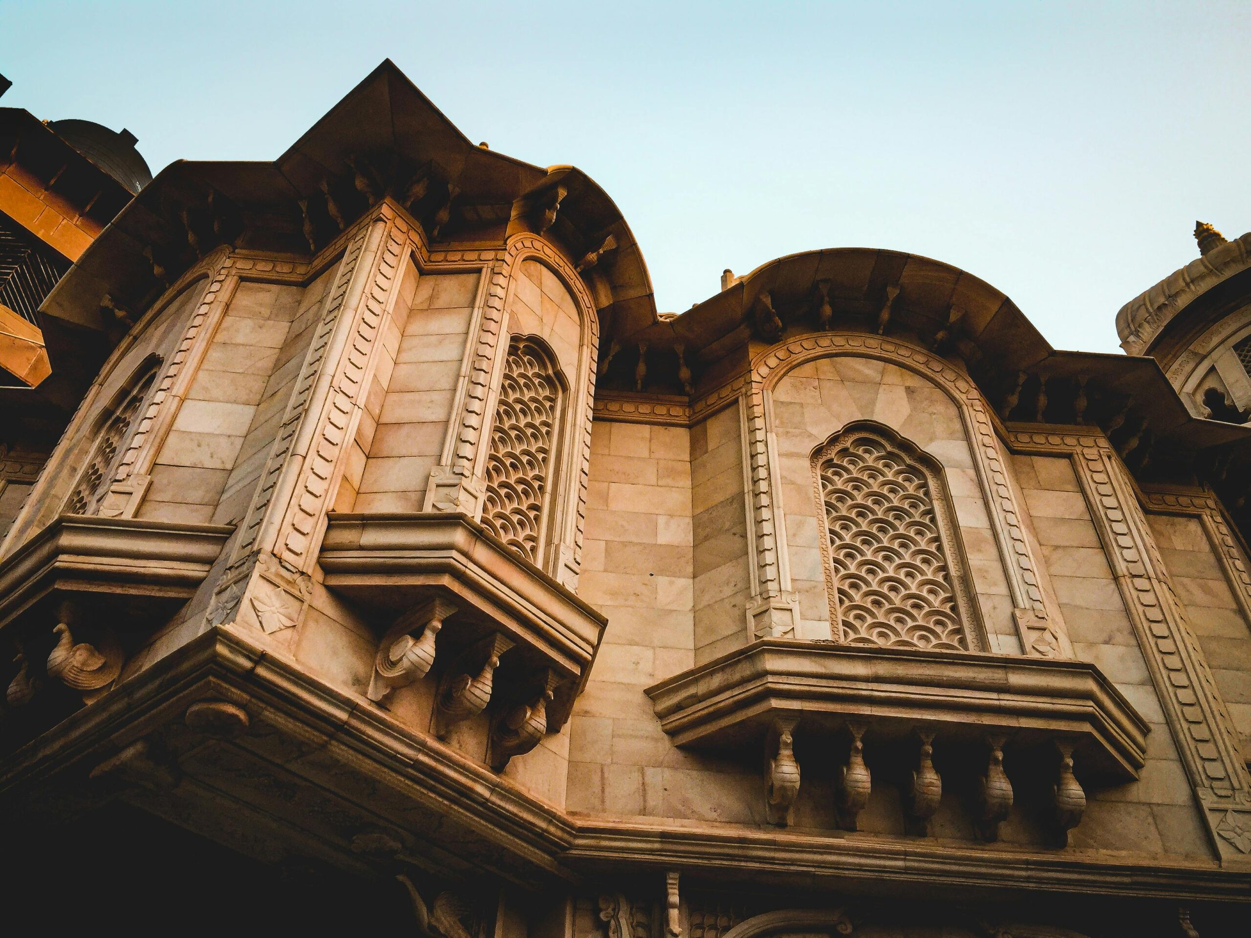 Low angle view of the intricate architecture of the ISKCON Temple in Vrindavan, showcasing its ornate stonework.